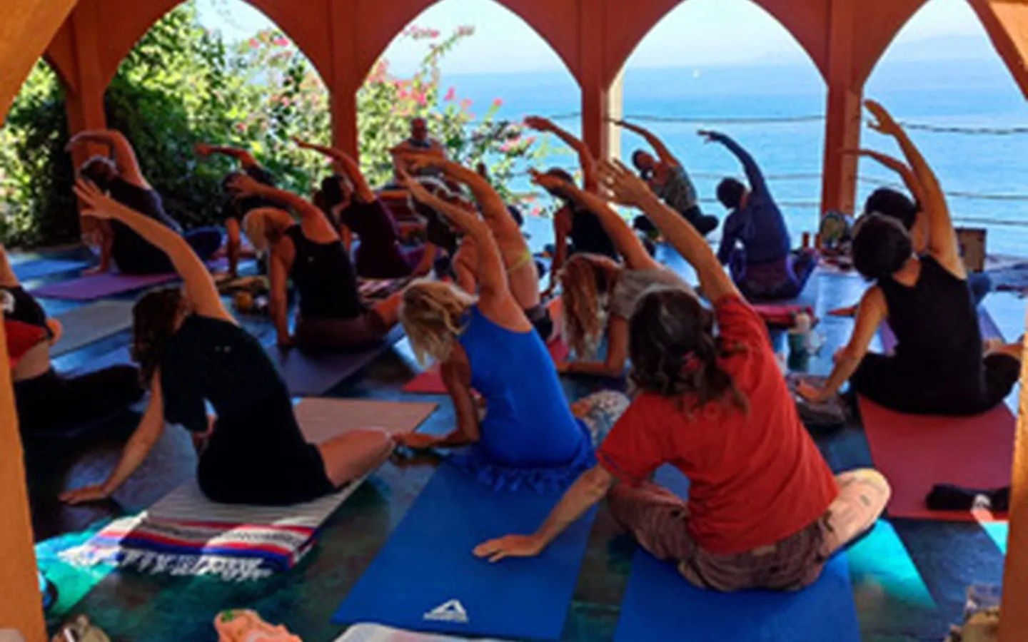 whats-included-yoga-1440x900-1-perf-v1.webp Group practicing yoga on an open-air deck overlooking the ocean