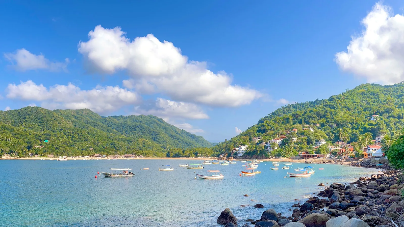 Breathe It In: Ocean Views in Yelapa, Mexico View across Yelapa Bay with boats, beach, and green hills beneath a blue sky.