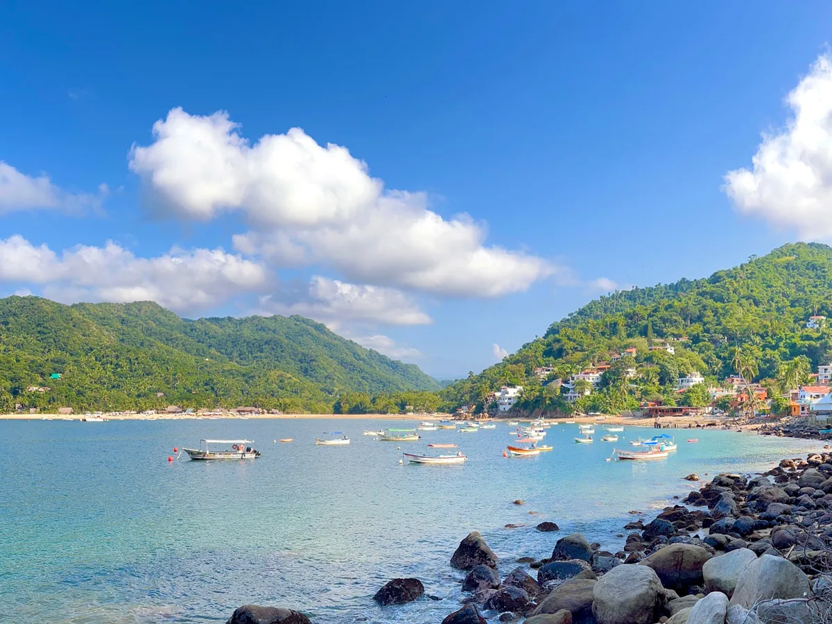 Breathe It In: Ocean Views in Yelapa, Mexico View across Yelapa Bay with boats, beach, and green hills beneath a blue sky.